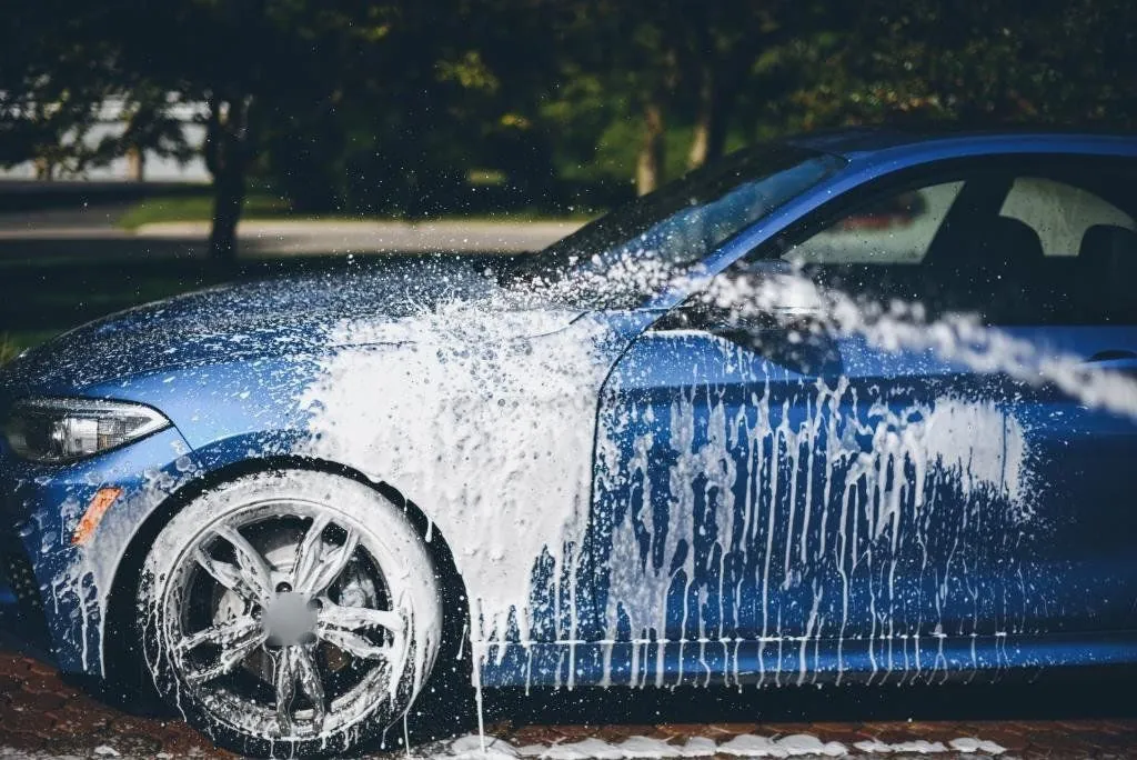 Auto azul cubierto de espuma durante el lavado