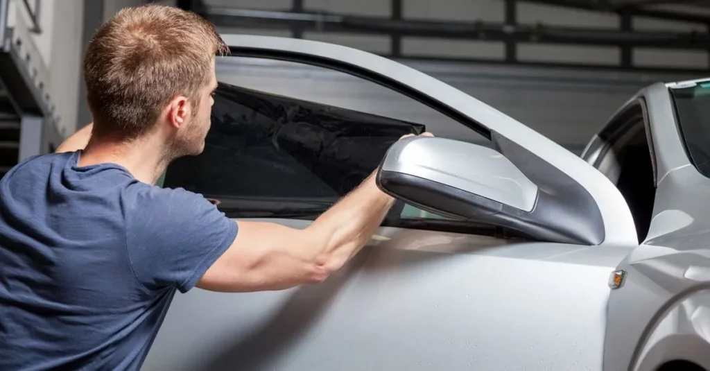 Instalación de película en la ventana lateral de un auto plateado